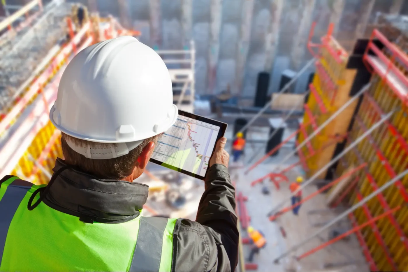 Engineer with hardhat on construction site using their tablet