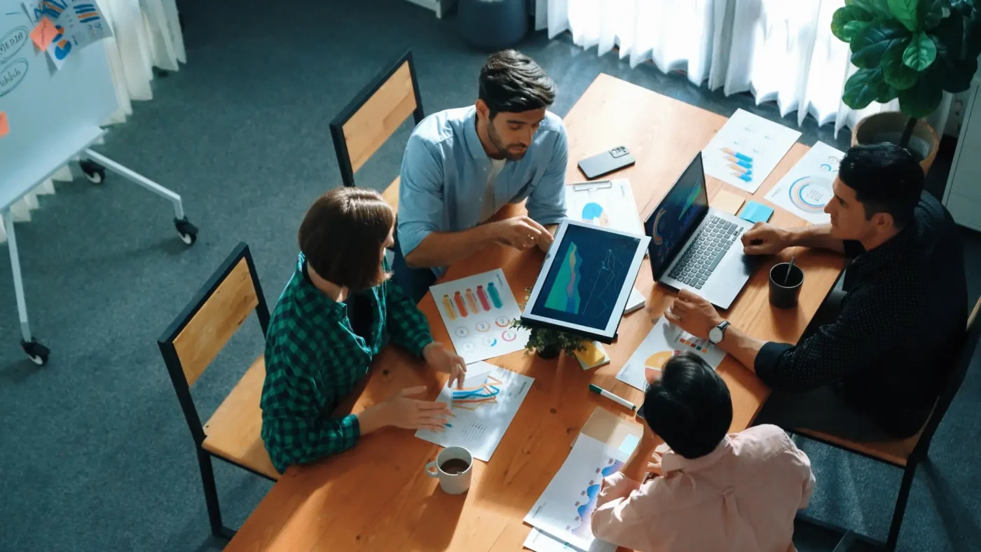 People sitting at a table reviewing graphs on their laptops