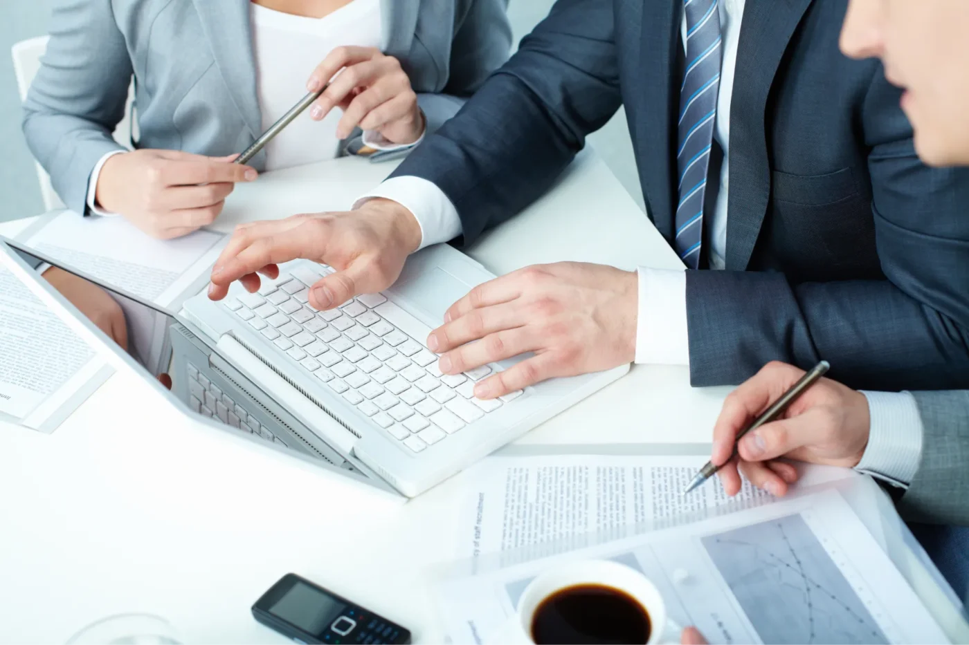 People working on a table with a laptop and papers